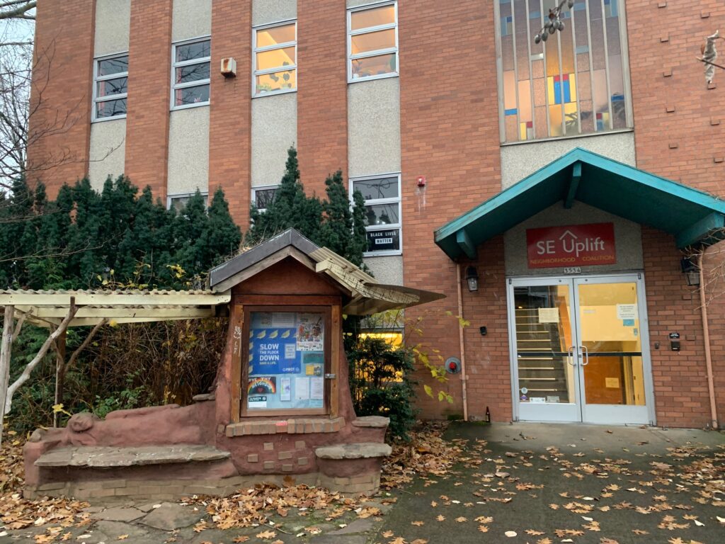 Main st entrance to the SE Uplift building, with some fall leaves scattered on the ground